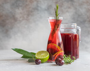 Lemonade or non-alcohol cocktail with cherry and lime, grey concrete background. Summer refreshment...