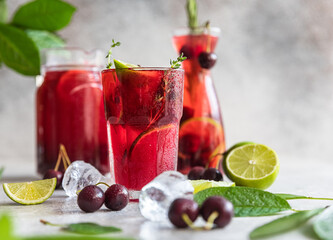 Cocktail or lemonade with cherries and lime, grey stone background. Mocktail. Cold summer drink.