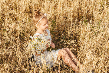 Little girl sitting in field, sunset light.