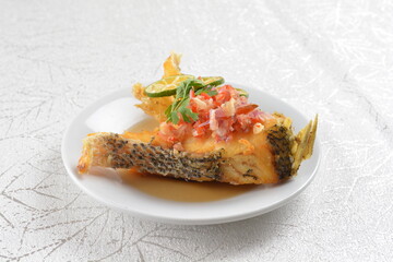 deep fried fresh grouper fish fillet in spicy and sour chilli lime sauce in white background asian halal seafood fine dining menu