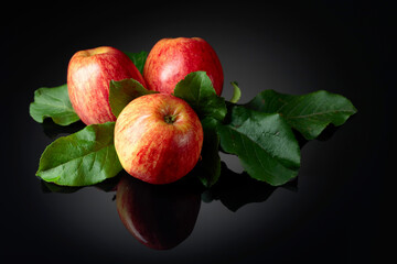 Fresh apples on a black reflective background.