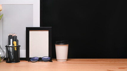 Empty picture frame, pencil holder, glasses and coffee cup on wooden table.