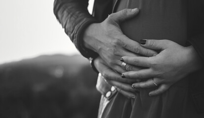 pregnancy. pair photo shoot. hands of a man and a woman on the abdomen. black and white. photo with noise. pregnancy photo shoot. place for text