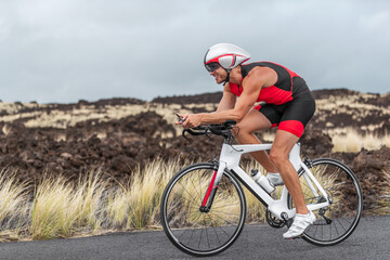 Cycling sport triathlete man biking on triathlon bike. Fit male cyclist on professional triathlon bicycle wearing aero helmet and trisuit for race in Kailua Kona, Big Island, Hawaii, USA. - obrazy, fototapety, plakaty