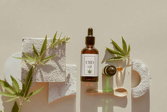 Various glass bottles with CBD oil, THC tincture and hemp leaves, capsule on beige background. Flat lay, minimalism. CBD oil cosmetics
