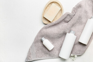 Bottles of cosmetic products, soap and towel on light background - obrazy, fototapety, plakaty