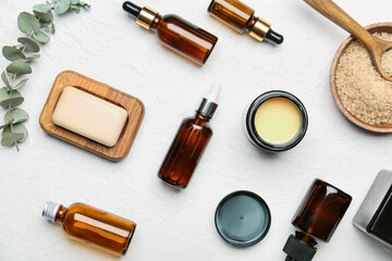 Different cosmetic products and sea salt on light background