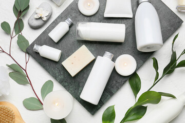 Composition with different cosmetic products and burning candles on light background