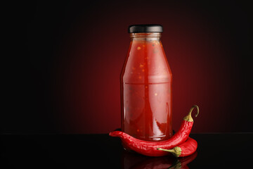 Bottle of chili sauce on dark background