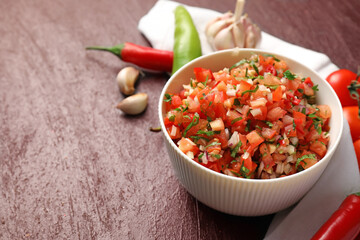 Bowl of tasty salsa sauce on dark background