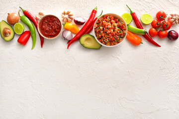 Bowls of tasty salsa sauces with products on white background