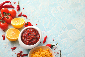 Bowl of tasty salsa sauce and products on color background