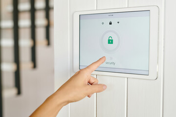 Naklejka premium Hand of young woman pointing at display with security symbol on the wall