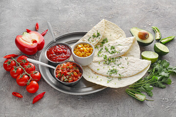 Bowls of tasty salsa sauces with tortilla and products on grunge background