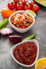 Bowls of tasty salsa sauces on grunge background