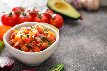 Bowl of tasty salsa sauce on grunge background