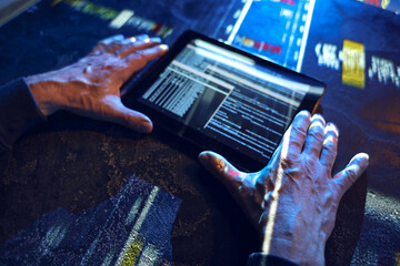 Hands of hacker with tablet computer on dark background