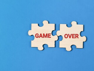 Phrase GAME OVER on jigsaw puzzle pieces against blue background.