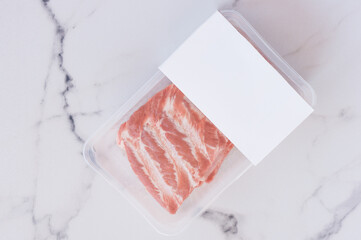 Raw pork ribs in vacuum packaging on marble background, logo mockup for design.