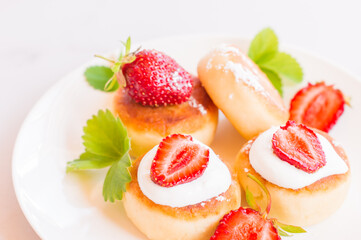 Syrniki, curd or cottage cheese pancakes withstrawberry, powdered suga on a white table