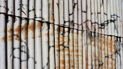 Old rusty corrigated iron wall with grafitti pattern