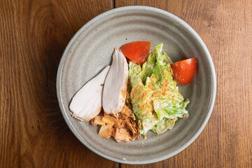 Chicken breast with lettuce salad and cherry tomatoes. Served in a bowl over rustic wooden background.