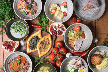 A lot of food on the table. Georgian cuisine: khachapuri, vegetable chicken salad, chicken broth soup, sweet dessert.