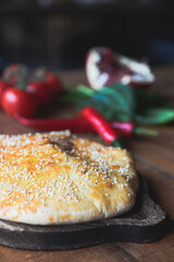 Khachapuri with cheese served on a wooden board over dark rustic wooden table. Traditional Georgian cuisine