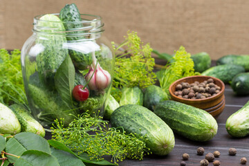 Cucumbers, head of garlic and cherry berry in glass jar.