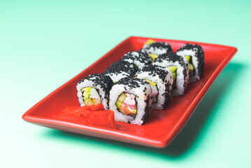 Tasty and fresh sushi set served in a red plate with wooden chopsticks. Close-up, selective focus on sushi.