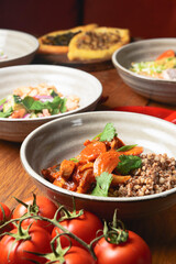Buckwheat porridge with fish in a ceramic plate over rustic wooden background.