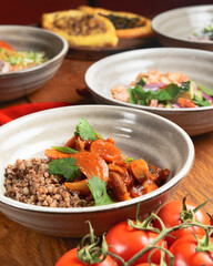 Buckwheat porridge with fish in a ceramic plate over rustic wooden background.