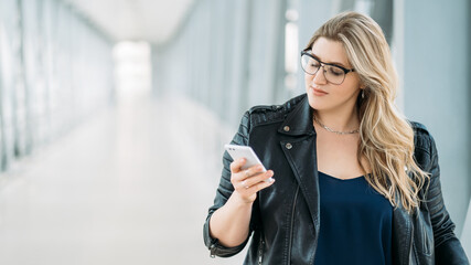 Mobile communication. Gadget people. Urban life. Body positive. Confident stylish overweight plus size obese woman using phone on light defocused copy space background.