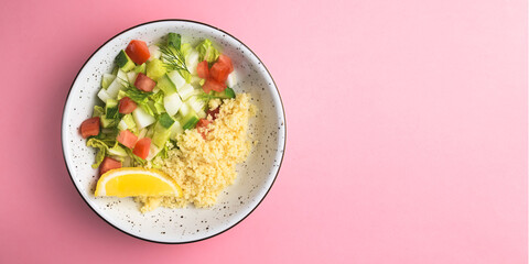 Bulgur with vegetables in a plate over pastel pink background. Delicious healthy dish in a bowl