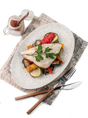 dietary dish, boiled dorado fish on a pillow of grilled vegetables top view on white background closeup. Selective focus. Main course