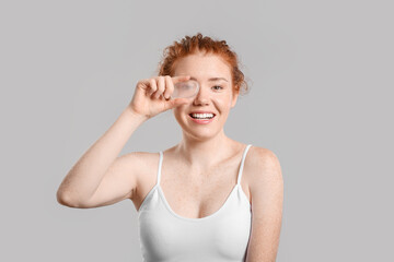 Beautiful young woman with makeup sponge on grey background