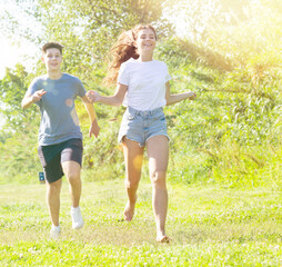 Obraz premium Young man and girl are running on the grass together