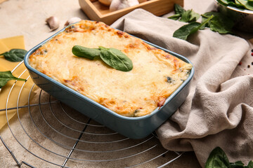 Baking dish with tasty green lasagna on grunge background