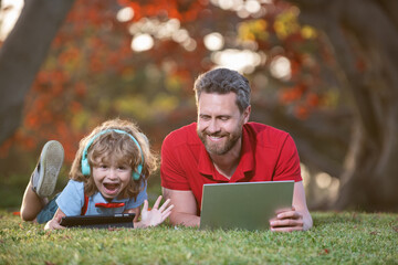 happy family use laptop for video call listen music in headphones in park, education online.