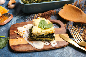 Board with tasty green lasagna on color background