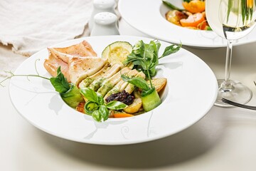 Close-up grilled squid with vegetables and a glass of white wine. Squid fillet baked with grilled vegetables with spicy green sauce. Delicious and healthy seafood. Mediterranean cuisine recipe