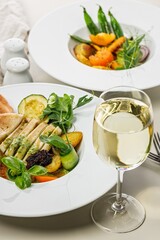 Vertical shot grilled squid with vegetables and a glass of white wine. Squid fillet baked with grilled vegetables with spicy green sauce. Delicious and healthy seafood. Mediterranean cuisine recipe