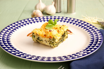 Plate with tasty green lasagna on color wooden background