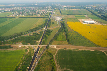 Land view through the airplane window. Fields, roads, rivers from a bird's eye view. Porthole. Look out the window of a flying plane. Top view of the ground