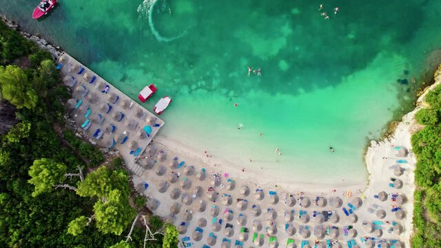 Aerial view of azure beach in Ksamil, Albania. Cozy sandy beach surrounded by green vegetation, people swim and sunbathe. Great place for summer vacation