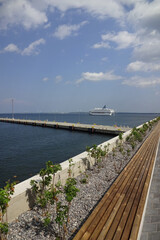 View from modern cruise terminal in Tallinn Old City Harbour. New concrete sea pier. Blue sky with clouds. Navy baltic sea. White ship leaving the port. Estonia, Baltic, Europe. July 2021.