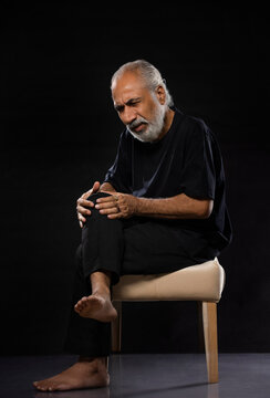 AN OLD MAN PRESSING KNEE JOINTS IN PAIN