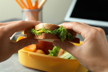 Workplace eating with female hands hold sandwich, close up
