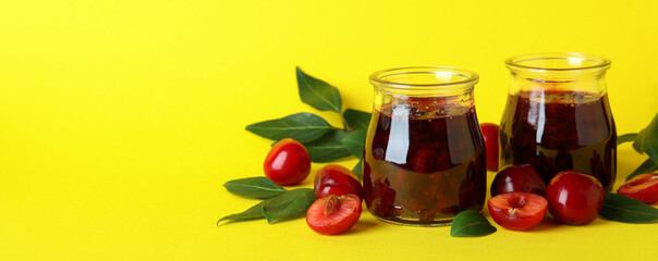 Cherry jam and ingredients on yellow background
