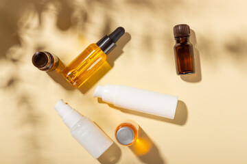 Tanning oil. A set of cosmetics next to seashells in the sunbeams on a pink background. Cosmetics for sun protection.